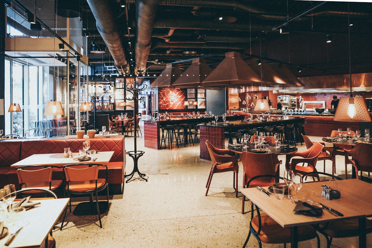 Warm, dim dining room with copper accents and leather banquettes