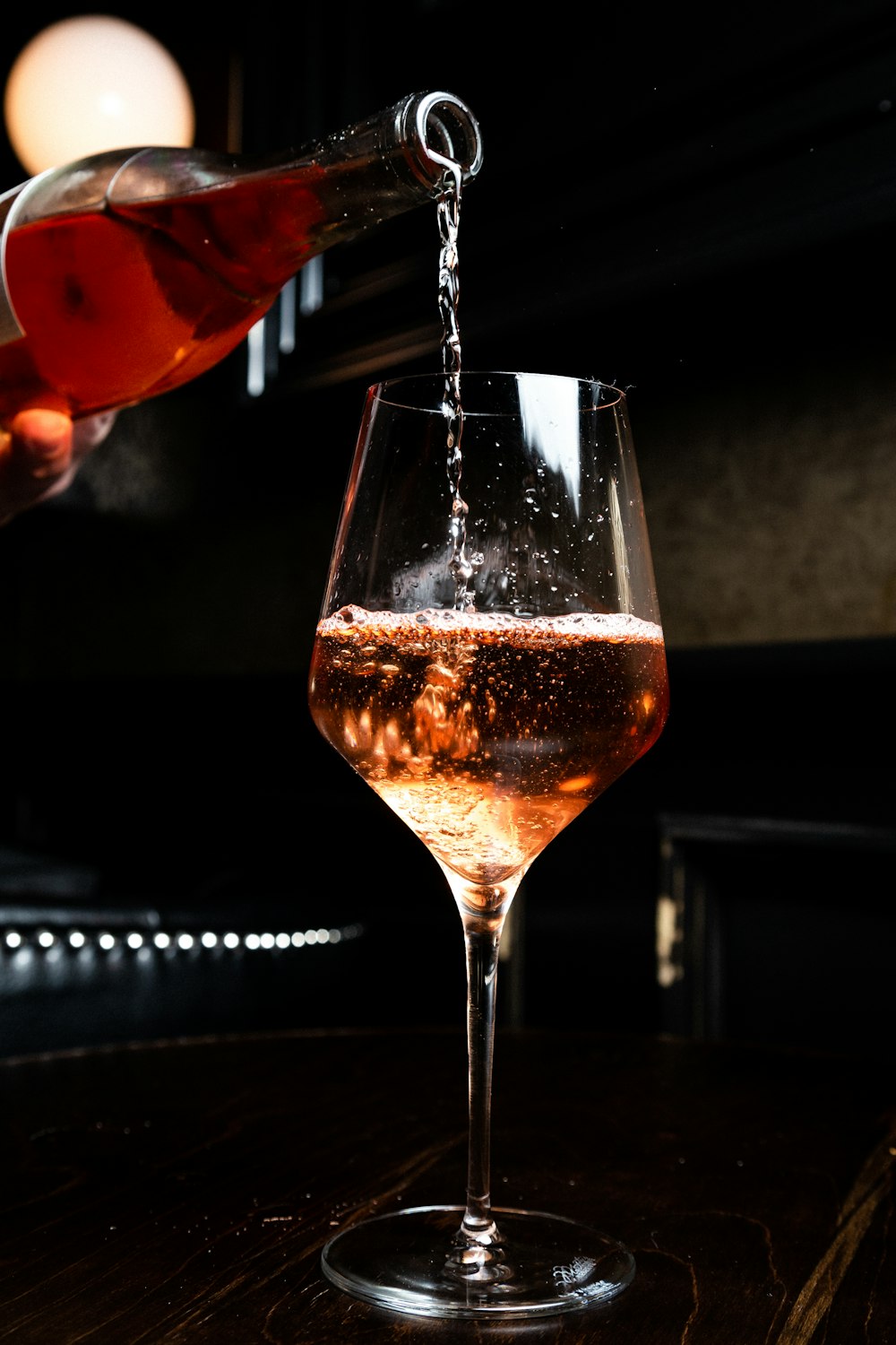 Wine being poured into a glass in a dark dining room